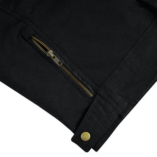 Close-up on the lower side panel of the black jacket, showing a brass-colored zippered expansion gusset and a gold snap button on the adjustable waist strap.