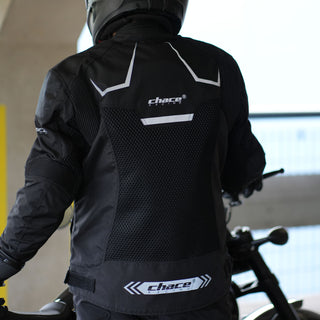 Rear view of a rider wearing the black Chace Volt motorcycle jacket, emphasizing the large breathable mesh back panel and the reflective "Chace Racing" logo strip at the lower hem.