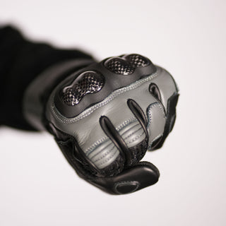 Close-up of the Stratus glove being worn in a fist shape, clearly showing the protective carbon fiber knuckle shield and the flexibility of the leather around the thumb area.