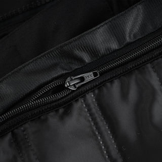 Extreme close-up of the internal zipper, showing the black pull tab and the quilted stitching pattern of the inner lining material.