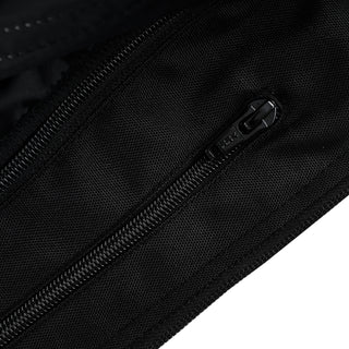 Close-up of a heavy-duty black coil zipper with a rubberized pull tab, set into the black textile material of an external jacket pocket.
