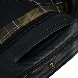 Close-up of a zippered slash hand-warmer pocket set into the leather near the main closure, with a peek of the internal tartan plaid lining visible.