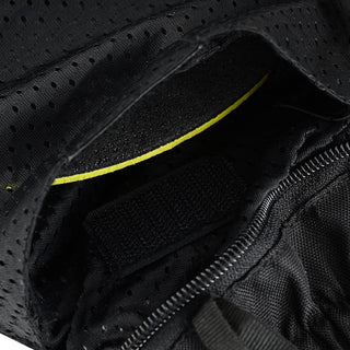 Close-up of an internal armor pocket opening, set within the perforated mesh lining, secured by hook-and-loop (Velcro), and accented by a thin strip of hi-visibility yellow trim.