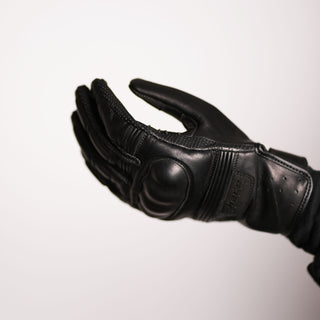 Palm-up view of the glove on a hand, highlighting the pre-curved shape of the fingers and the profile of the hard knuckle protector on the back of the hand.