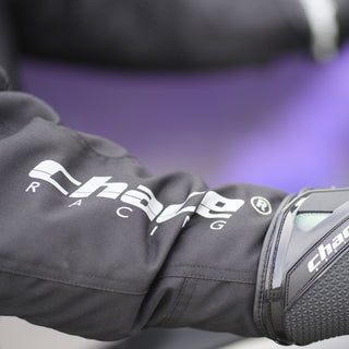 Close-up of the jacket sleeve showing the large white "Chace Racing" graphic logo printed on the textile, interfacing with a black leather or textile riding glove.
