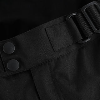 Close-up of the trouser's waist, showing the black webbing adjustment strap with a plastic buckle, positioned next to the dual snap buttons for a customized fit.